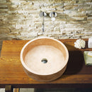 Troia Light Travertine Cylinder Round Above Vanity Bathroom Sink Honed (D)16" (H)6" installed above wooden vanity and wall mount chrome faucet and split face marble wall tiles green towel on the vanity