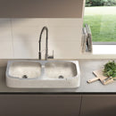 Troia Light Travertine Curved Apron Double Bowl Farmhouse Sink (W)18" (L)36" (H)7" installed kitchen above countertop wooden cutting board and nice backyard showing from the window