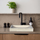 Troia Light Travertine Rectangular Above Vanity Bathroom Vessel Sink (W)16" (L)27.5" (H)4" installed bathroom above vanity black faucet liquid soap and green plant on the top shelf