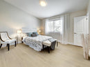 Neatly arranged bedroom with a bed, chair, and lamp. K-02VH