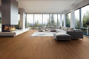 Modern living room with a fireplace, sectional sofa, and large windows overlooking trees. K-07VH