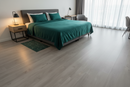 Modern bedroom with a green bedspread and wooden flooring.