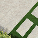Beige stone tiles with a green grass strip and plants on the side