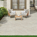 Outdoor patio with wooden chairs, table, and cushions on a stone patio.