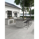 Outdoor kitchen with bar stools and grill area near a body of water.