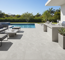 Outdoor patio area with pool, chairs, and plants on a sunny day.