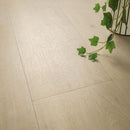 Close-up of light wood flooring with a plant in the corner