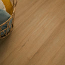 Close-up of a wooden floor with a wicker chair partially visible.