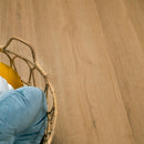 Close-up of a wooden floor with a wicker chair and cushions.