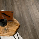 Wine glass on a wooden stool with a notebook and pen against a wooden floor background