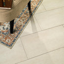 Close-up of a patterned rug on a tiled floor with a chair partially visible.
