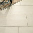 Close-up of beige tiles with a portion of a patterned rug visible