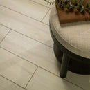 Round cushioned stool with a plant on a light wood floor