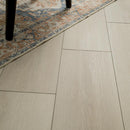 Close-up of a wooden floor with a part of a rug visible at the top left corner.