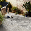 Alaska Silver Travertine Pattern Tumbled Pavers - Full Truckload patio view with magazines on floor and wooden chair towel on top plants 