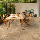 Aspendos Beige Travertine Pattern Tumbled Pavers - Full Truckload patio wooden dining table plates, bread some flowers on top black bike on the back ground.