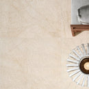 living style cream porcelain pavers 24x24in matte floor tile LPAVNLIVCRE2424 installed on living room floor grey couch with coffee table and plant closeup