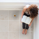 mayra white limestone 24x24 woman sitting reading book closeup