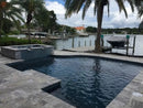 silver travertine pavers tumbled pattern installed around pool Miami wide view
